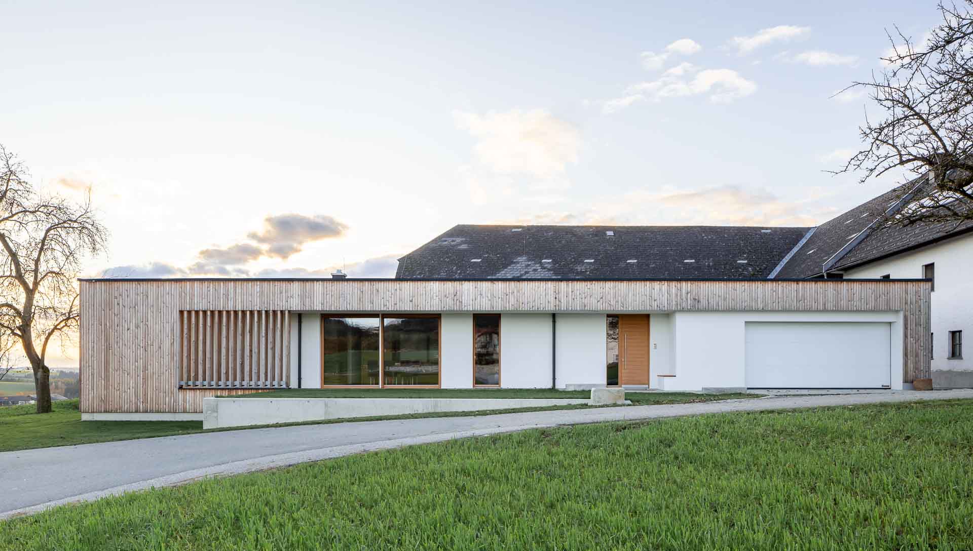 bungalow im grünen, Lärchenfassade, architekturfotografie Twilight, Sonnenuntergang, stimmungsvolle Lichtstimmung, klare Linien, Holzlamellen, modern, klare Linien